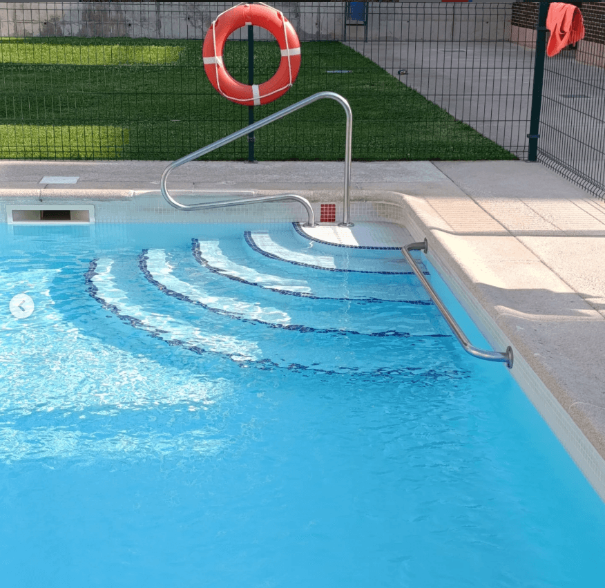Detalle de escaleras de piscina con salvavidas